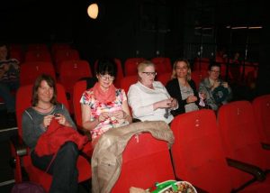 Frauen sitzen im Kinosaal und stricken
